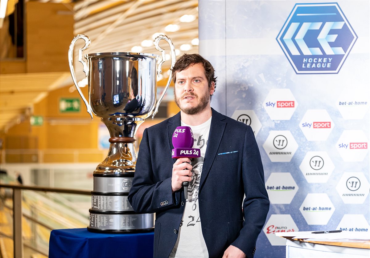 PULS 24 anchorman Martin Pfanner and the league trophy